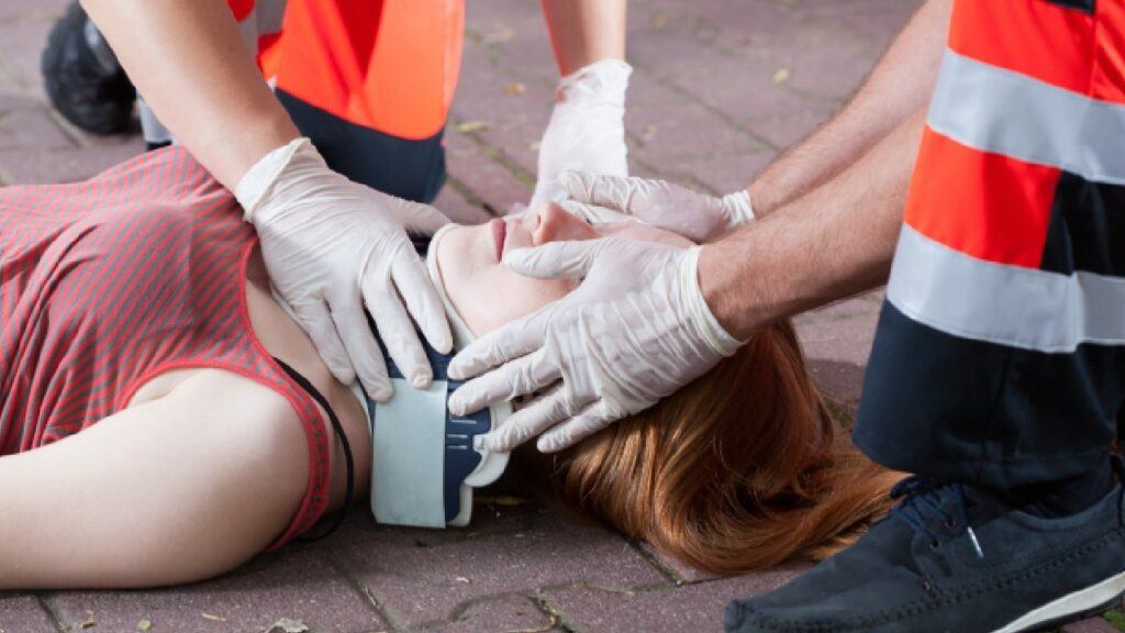 Woman receiving first aid for a spinal injury while laying on the ground