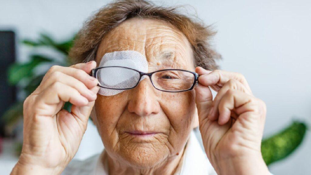 elderly lady putting glasses on over the top of a bandaged eye injury