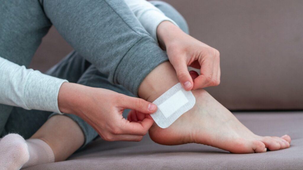 Woman putting a blister bandaid on her foot