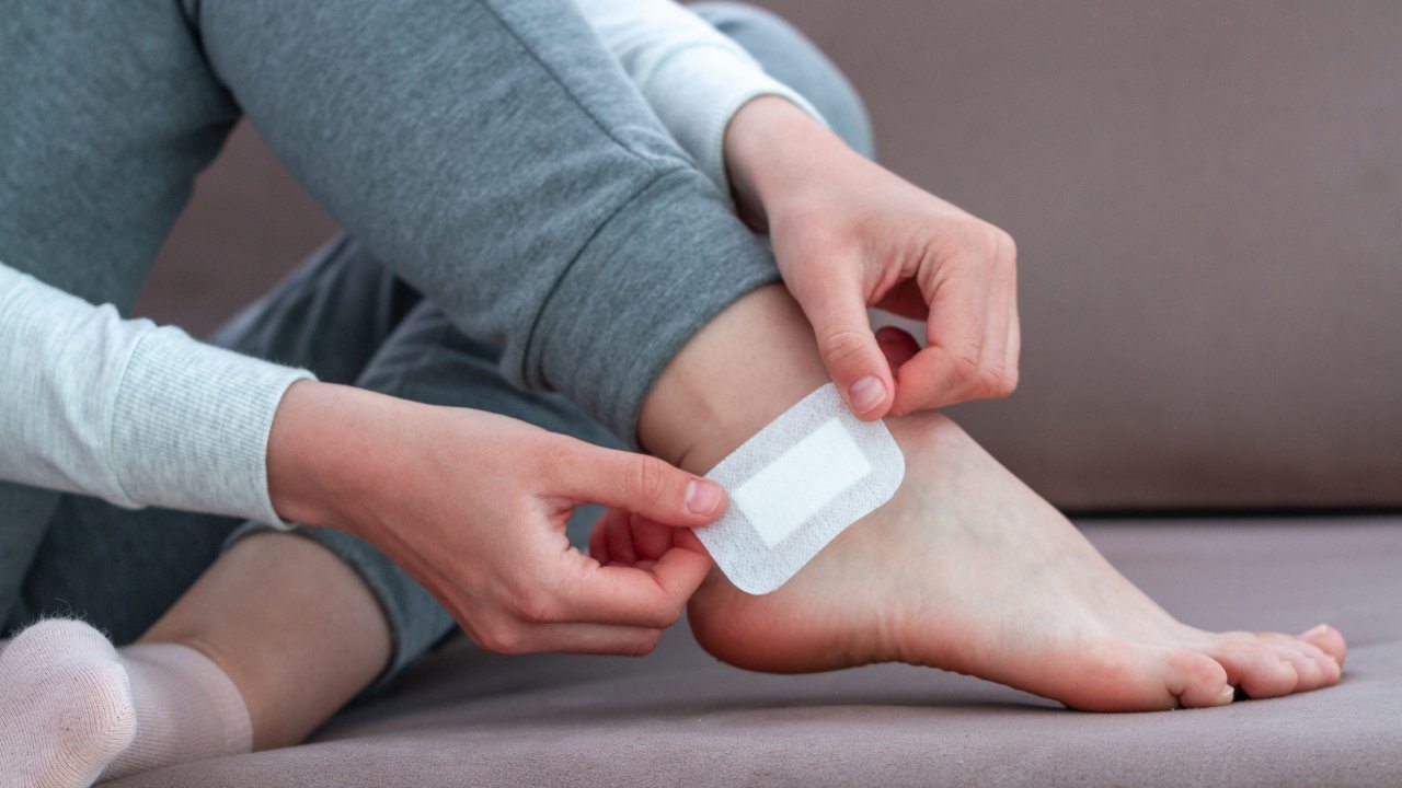 Woman putting a blister bandaid on her foot